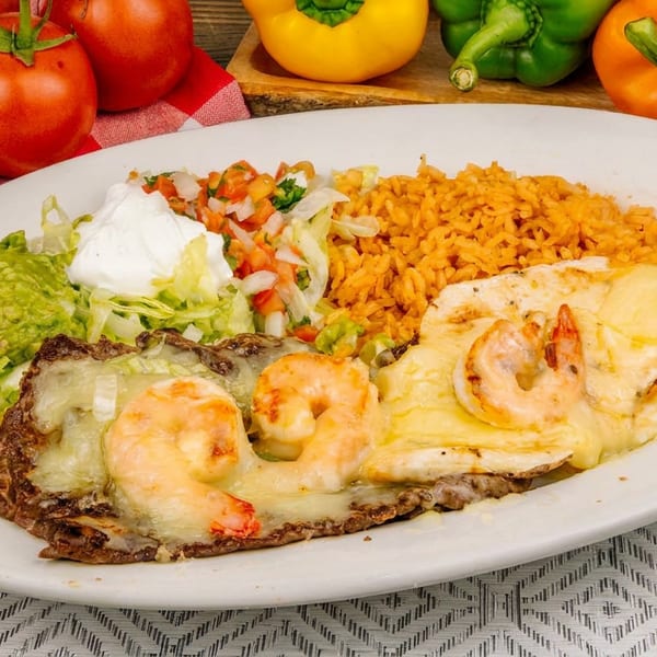A white plate with shrimp and cheese, rice, guacamole, pico de gallo, and lettuce.